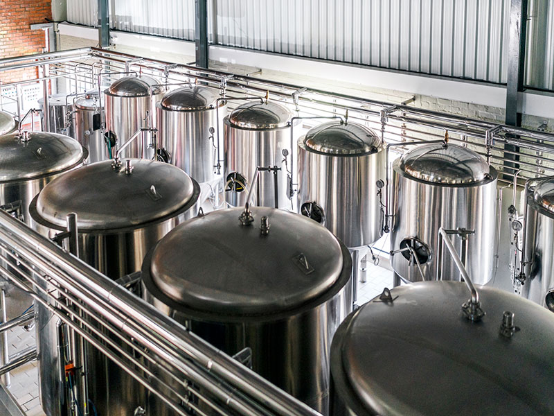 Two rows of large stainless steel vats in a brewery